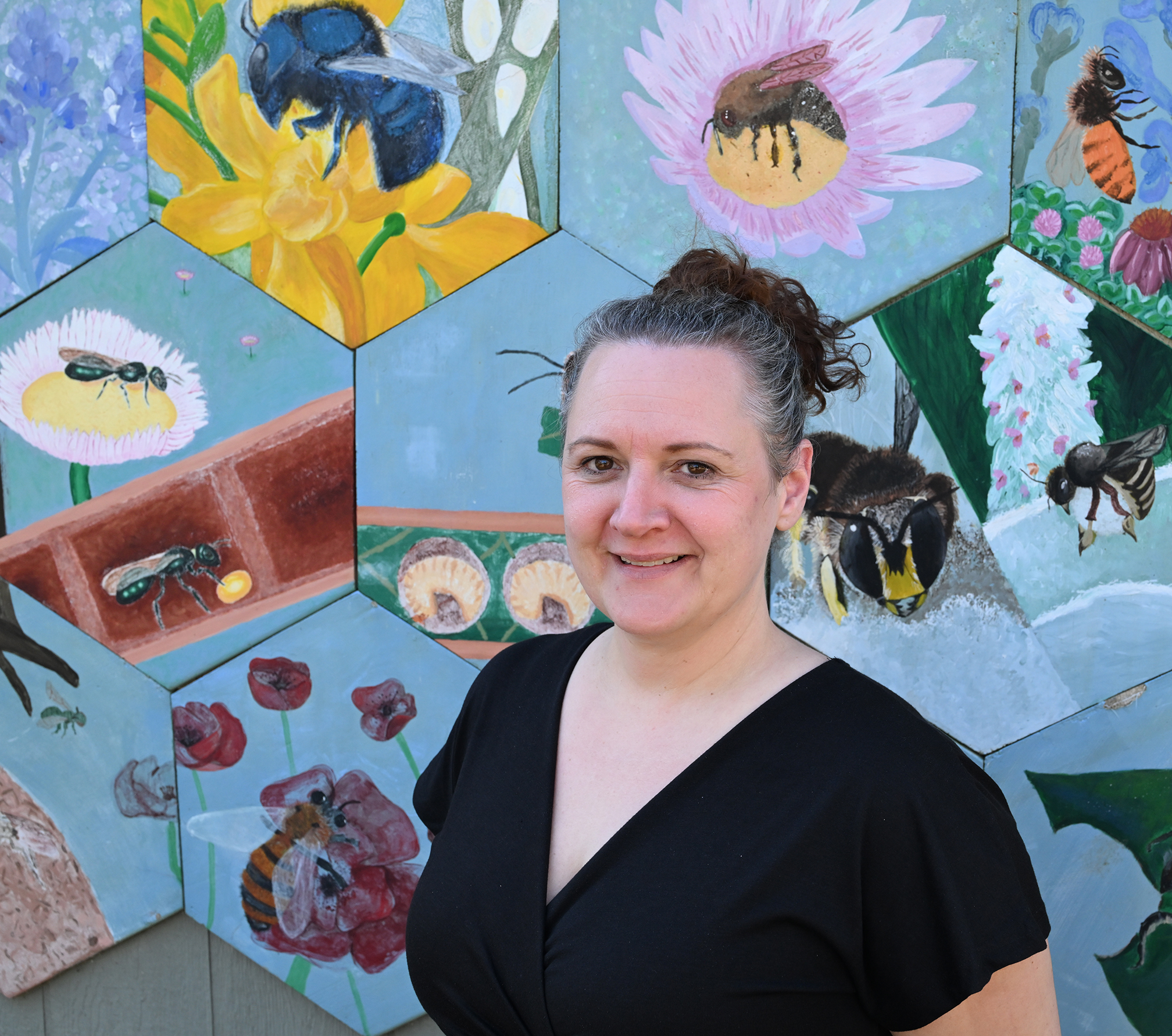 Professor Elina Nino in front of a wall of mosaic-ceramic bees at the UC Davis Bee Haven.