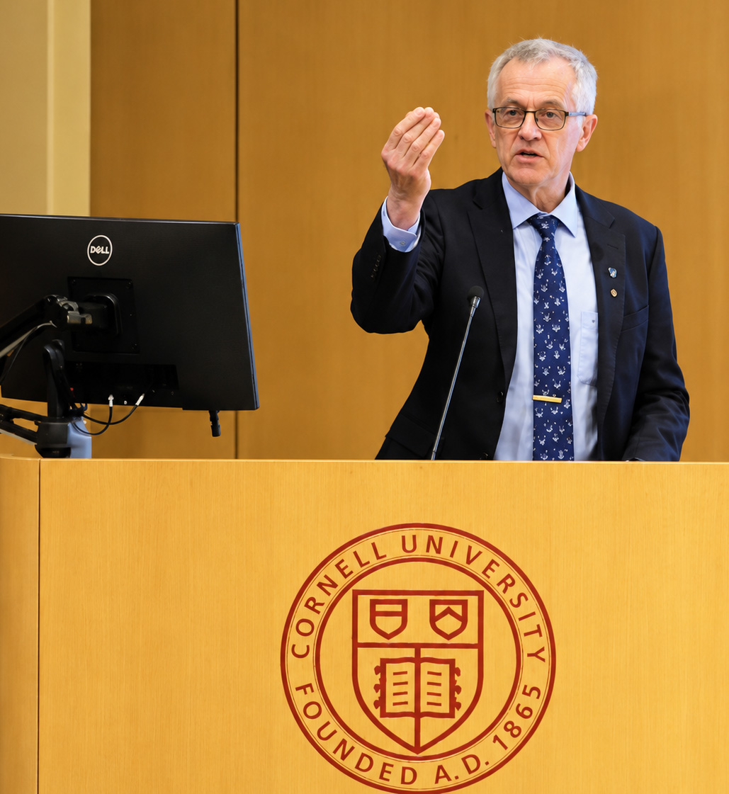 Walter Leal gesturing at lectern bearing Cornell University seal