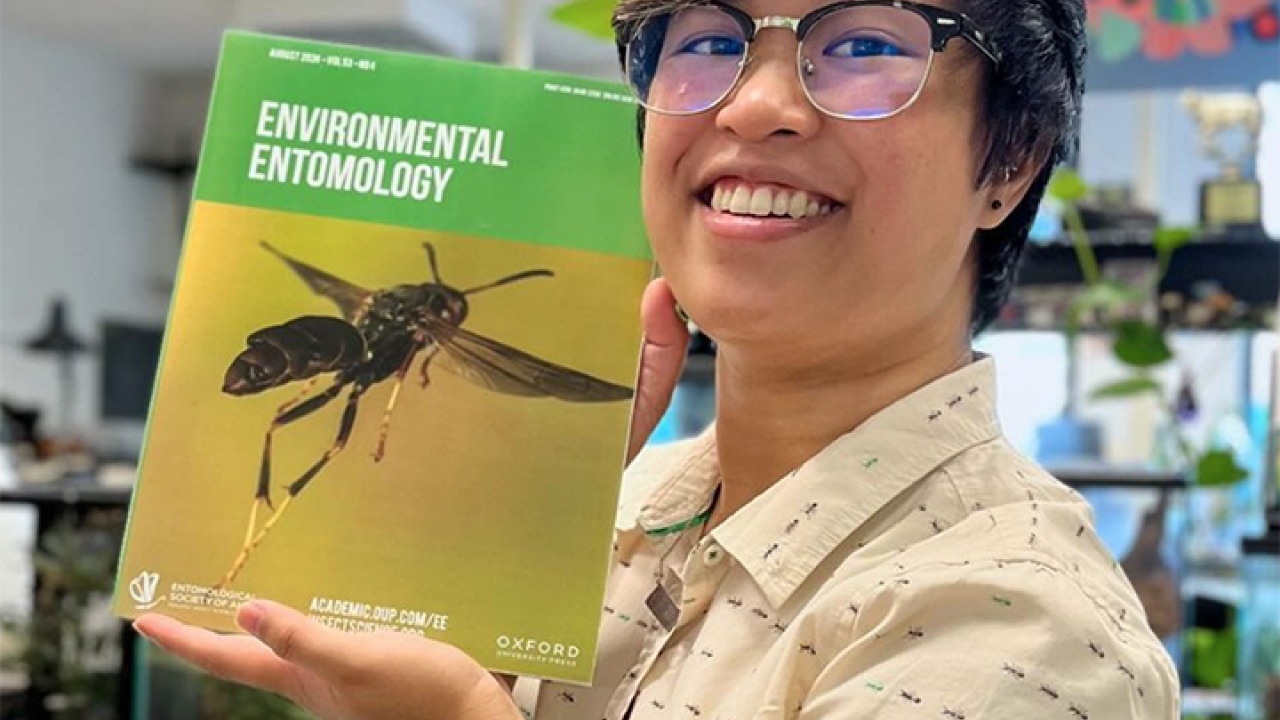 UC Davis alumna RJ Millena, doctoral candidate at the Richard Gilder Graduate School, American Museum of Natural History, holds the August issue of the journal 'Environmental Entomology." Her research made the cover. (Photo by Lohit Garikipati)