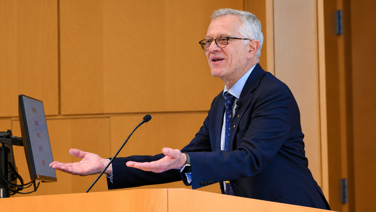 Walter Leal smiling and gesturing at wooden lectern (photograph)