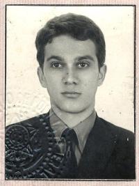 Black-and-white passport photo of young man in suit and tie, embossed seal