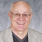 Steve Clement, with glasses in gray blazer, studio portrait, neutral background